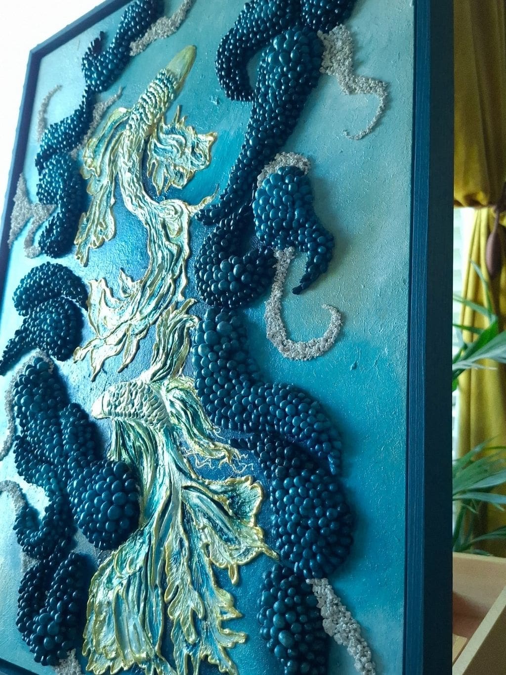 Textured mixed media artwork with hand-sculpted fish shapes in layered blue acrylic tones, surrounded by repeated dark blue sculptural forms, presented in a custom dark blue frame.