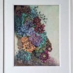 A framed painting of colourful succulents in shades of purple, red, yellow, and green, clustered together on a textured surface with a light background.